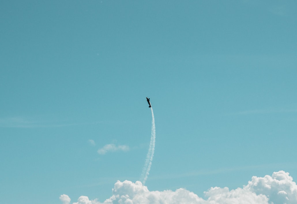 Small plane flying among clouds in an azure blue sky.